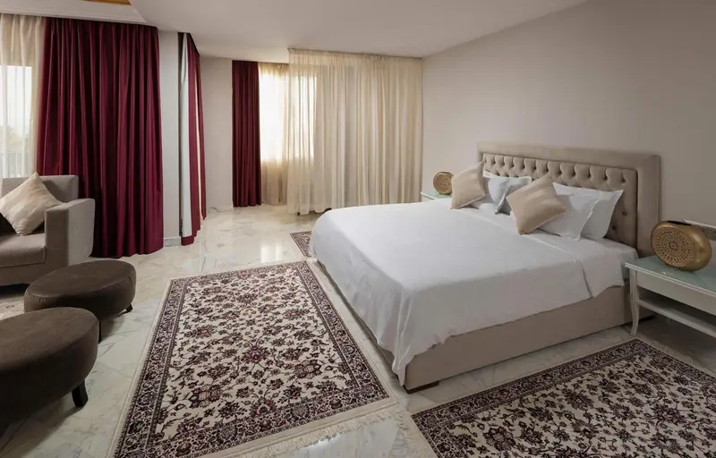 Une chambre lumineuse avec un grand lit et un coin salon.