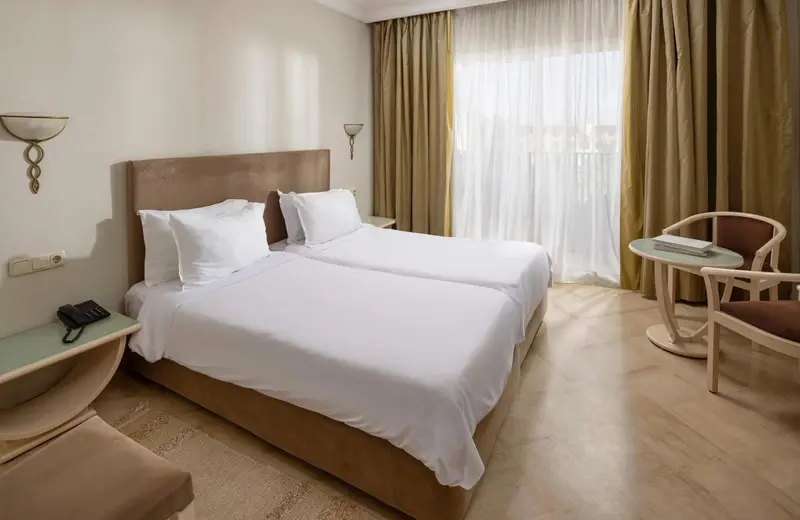 Une chambre lumineuse avec un grand lit et un coin salon.