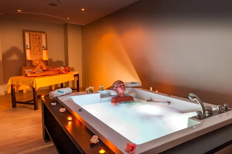 Une femme se fait masser sur une table et une autre se détend dans un jacuzzi.