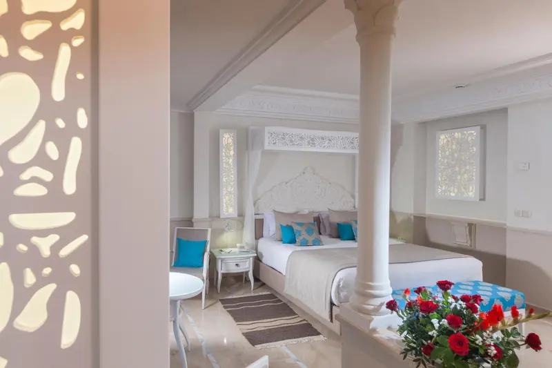 Une chambre lumineuse avec un grand lit à baldaquin et une décoration soignée.