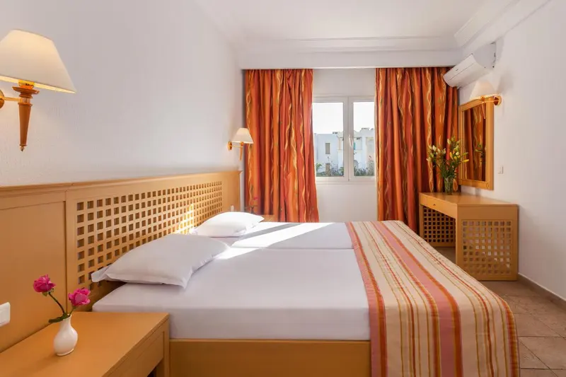 Une chambre lumineuse avec un lit double et des rideaux orange.