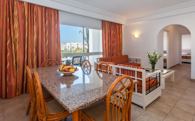 Espace de vie lumineux avec table à manger et canapé près d'une fenêtre.