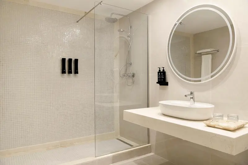 Une douche à l'italienne moderne avec un grand miroir rond.