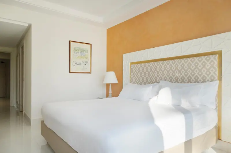 Une chambre lumineuse avec un grand lit recouvert de draps blancs.