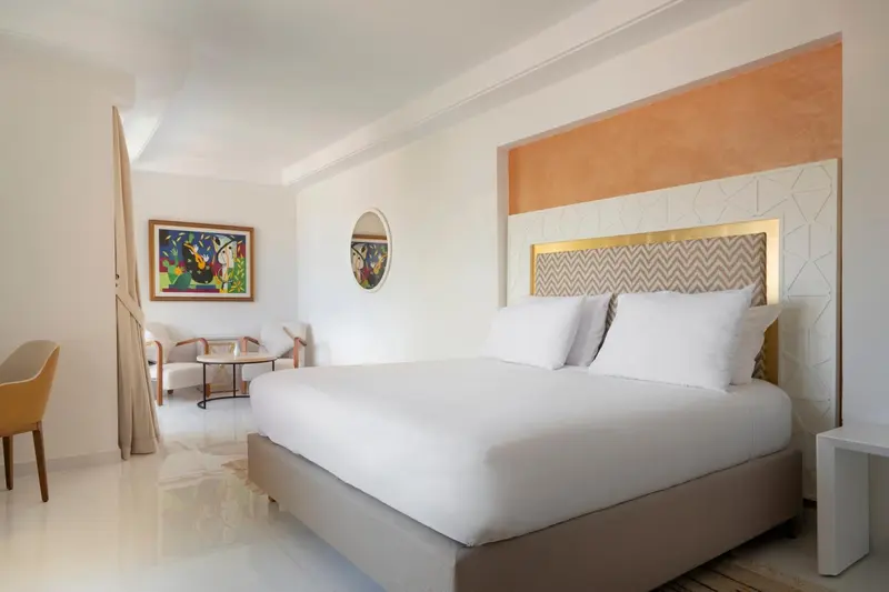 Une chambre lumineuse avec un grand lit recouvert de coussins blancs.