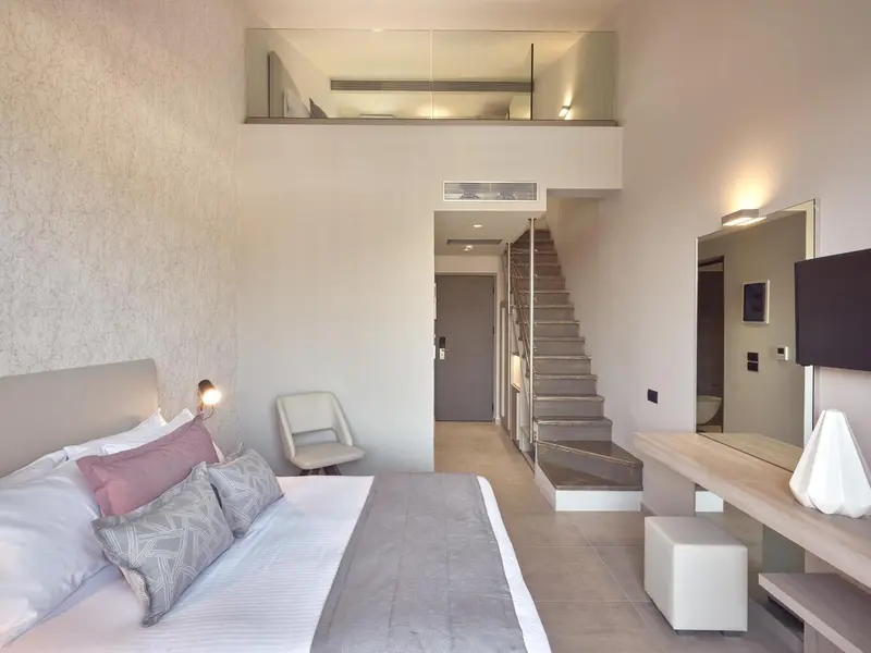 Une chambre moderne avec un lit et un espace mezzanine accessible par un escalier.