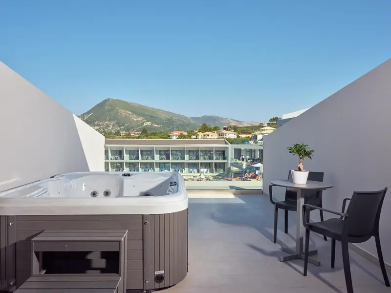 Un jacuzzi sur une terrasse avec vue sur un paysage montagneux et une piscine.