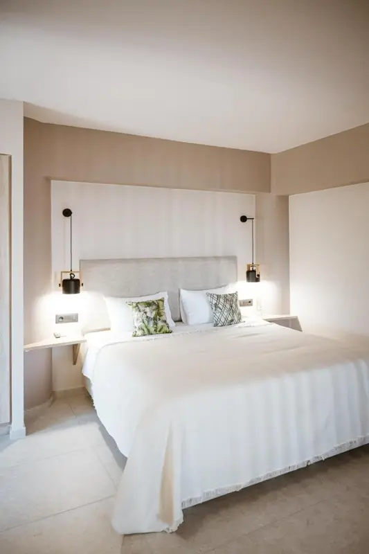 Une chambre lumineuse avec un grand lit recouvert de draps blancs.