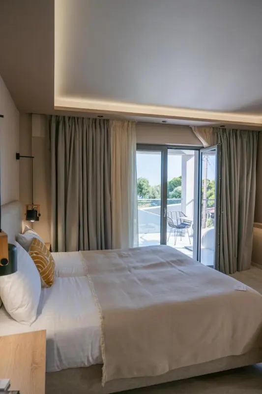 Une chambre lumineuse avec un grand lit donnant sur une terrasse.