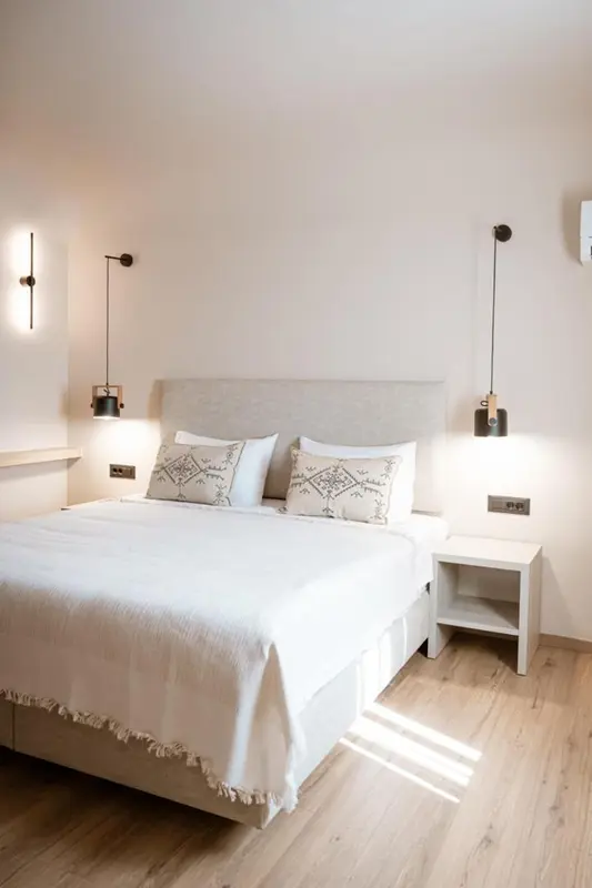Une chambre lumineuse avec un grand lit recouvert de linge blanc.