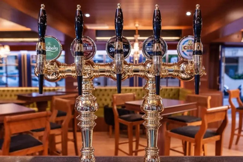 Robinetterie dorée avec plusieurs tireuses de bière sur un comptoir de bar.