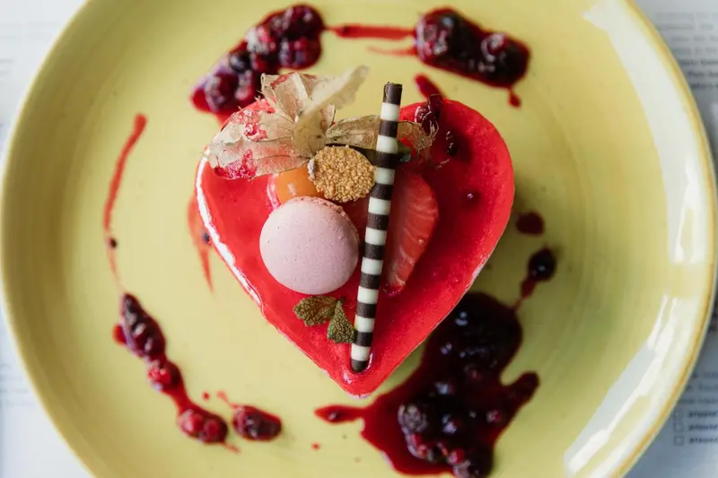 Assiette décorative avec une pâtisserie en forme de cœur et des fruits rouges.