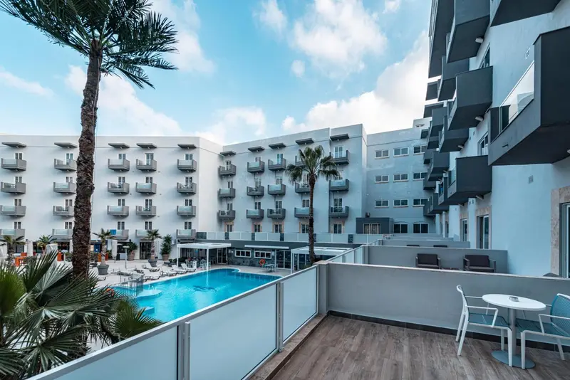 Vue d'un bâtiment moderne avec une piscine et des palmiers.