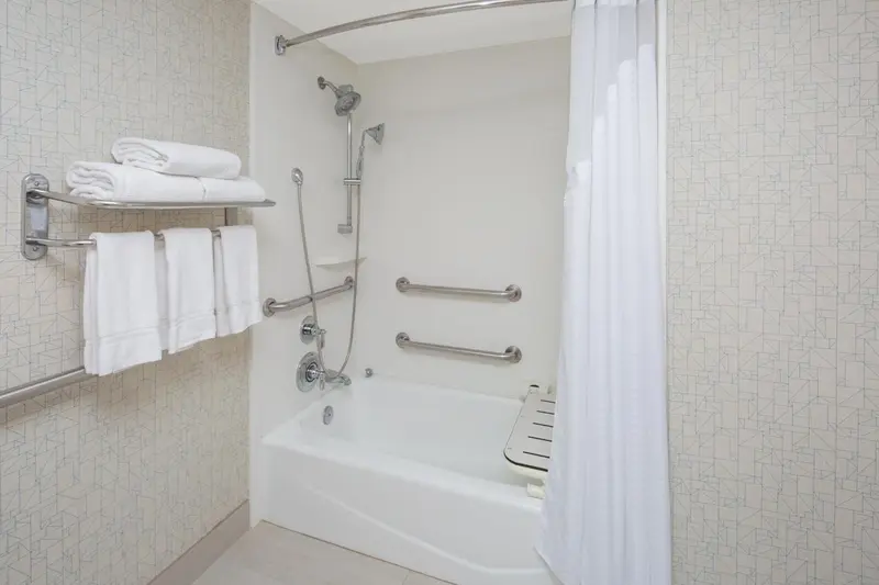 Une salle de bain claire avec baignoire et rideau de douche.