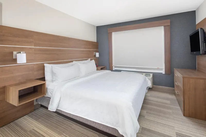 Une chambre d'hôtel avec un lit double et une commode en bois.