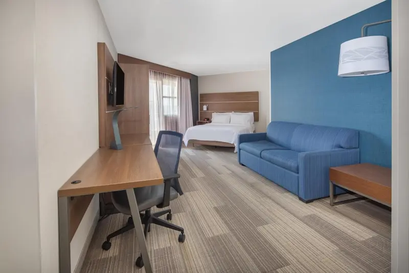 Une chambre lumineuse avec un lit, un bureau et un canapé.
