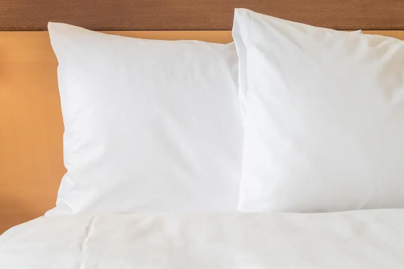 Oreillers blancs sur un lit avec une tête de lit orange.