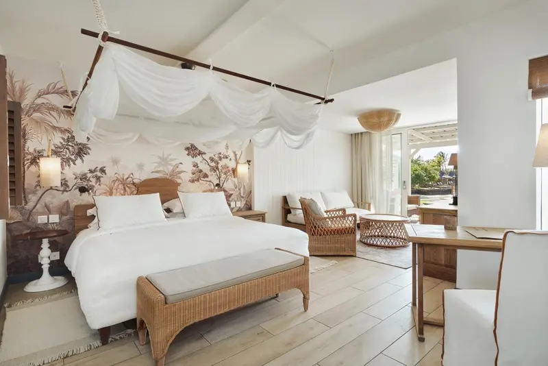 Une chambre lumineuse avec un grand lit à baldaquin et un coin salon.