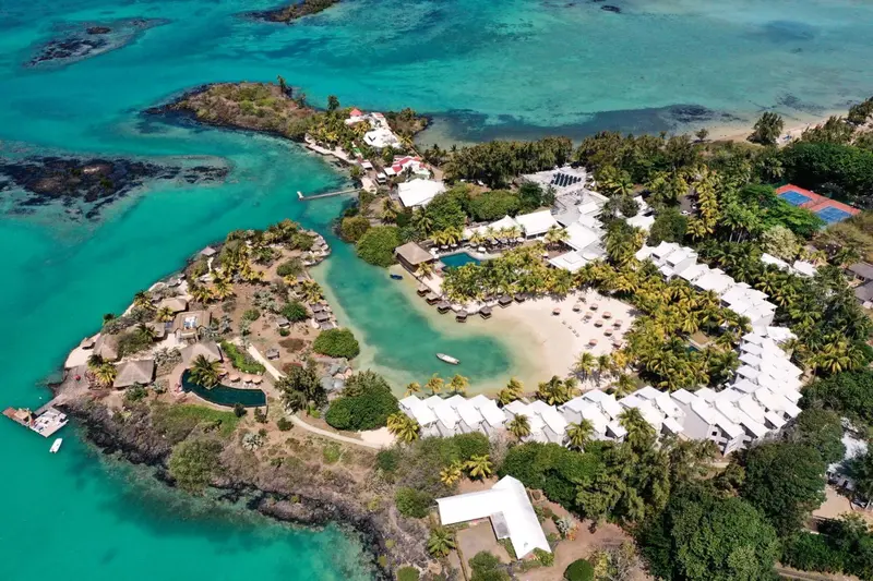 Vue aérienne d'un complexe hôtelier bordant une plage de sable blanc et une eau turquoise.
