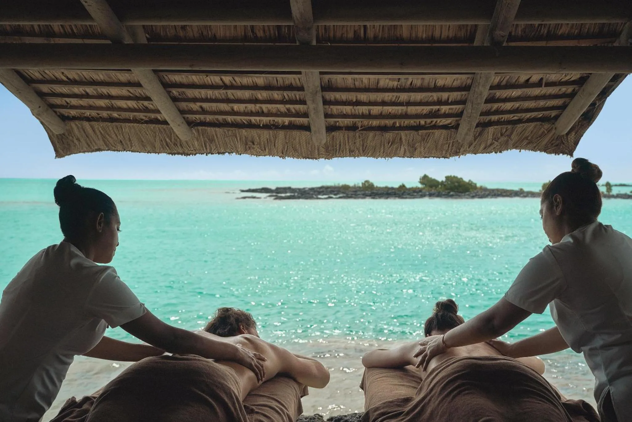 Deux femmes allongées reçoivent un massage en bord de mer.