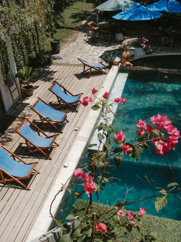 Transats bleus alignés au bord d'une piscine rectangulaire entourée de végétation.