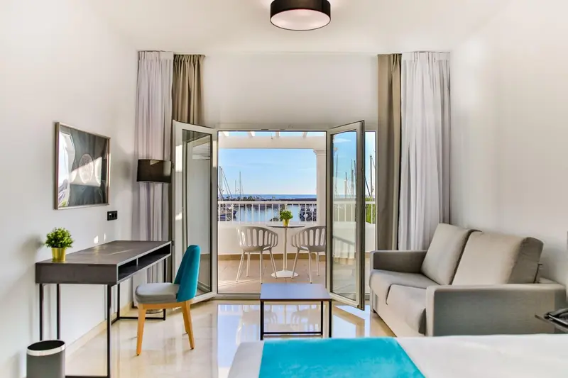 Une chambre lumineuse s'ouvre sur une terrasse avec vue sur le port.