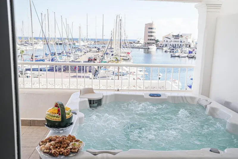 Jacuzzi sur une terrasse avec vue sur un port de plaisance ensoleillé.