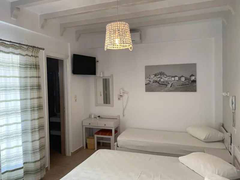 Une chambre lumineuse avec deux lits simples et un tableau décoratif au mur.
