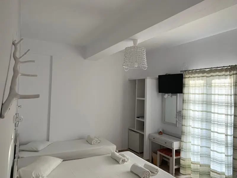 Une chambre lumineuse avec un lit blanc et une coiffeuse.