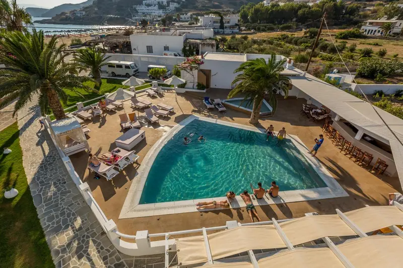 Vue aérienne d'une piscine entourée de transats et de palmiers.