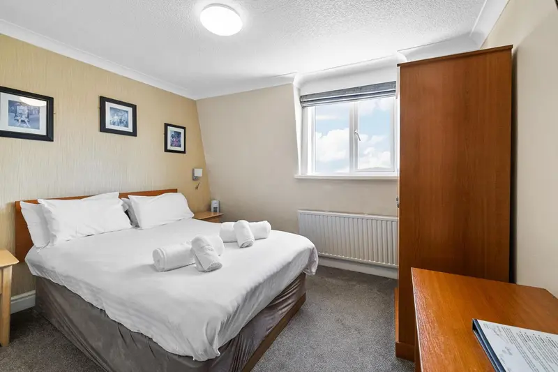 Une chambre lumineuse avec un grand lit et un bureau.