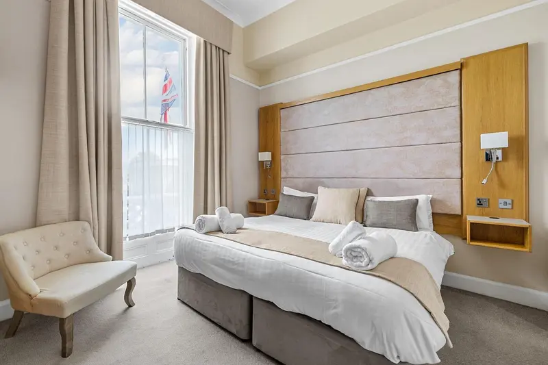 Une chambre lumineuse avec un grand lit et un fauteuil.