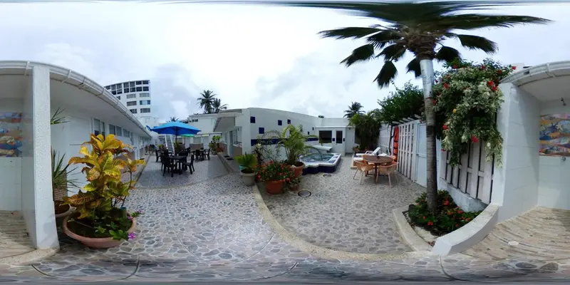 Une cour intérieure aménagée avec des tables, des chaises et des plantes tropicales.