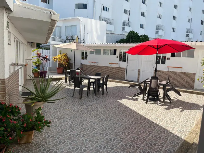 Une cour pavée avec des tables et des parasols colorés devant des bâtiments.