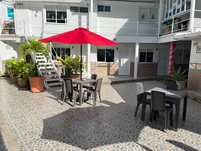 Terrasse ombragée avec tables et chaises près d'un bâtiment blanc.