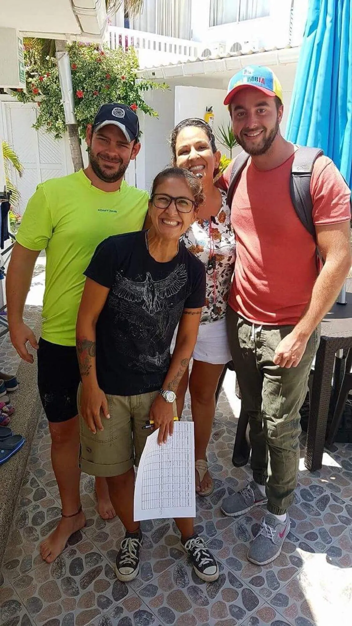 Quatre personnes souriantes posent devant une terrasse ensoleillée.