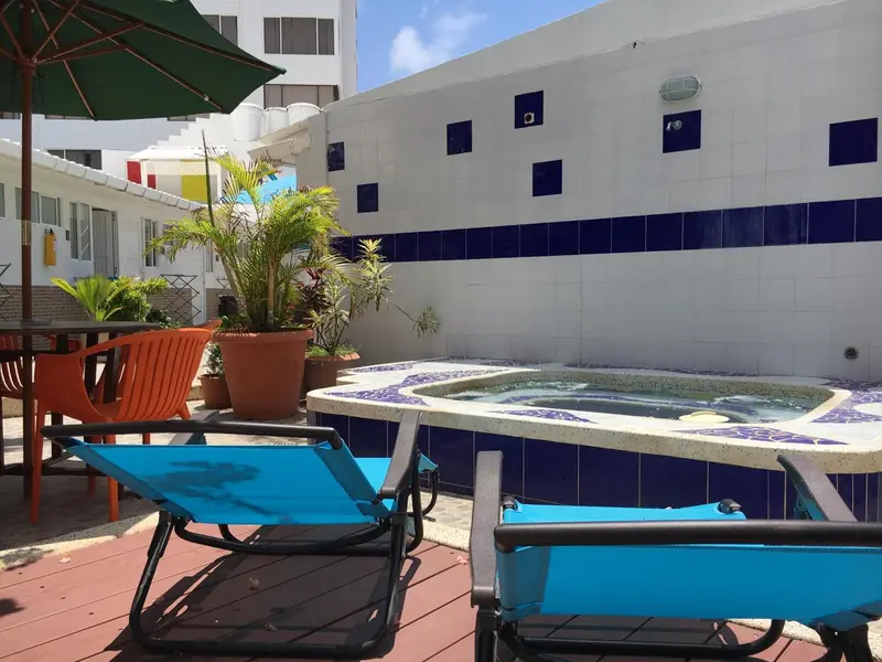 Terrasse avec transats et jacuzzi dans un espace extérieur ensoleillé.