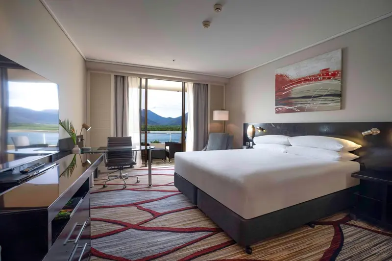 Chambre lumineuse avec un grand lit et une vue sur la mer.