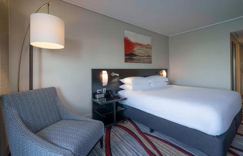 Une chambre d'hôtel moderne avec un lit double et un fauteuil.