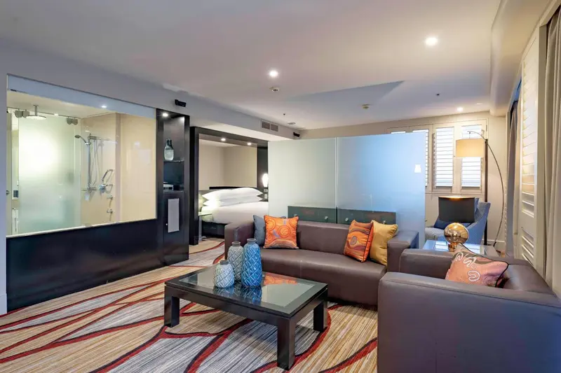 Un salon moderne avec canapé et table basse, donnant sur une chambre à coucher.