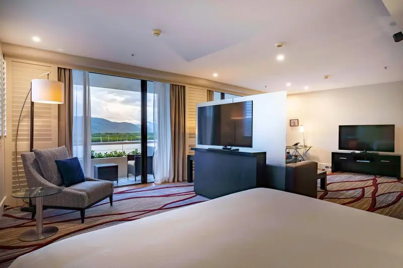 Une chambre spacieuse avec un grand lit et un coin salon donnant sur une vue extérieure.