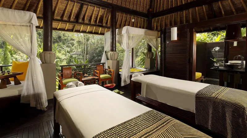 Espace de relaxation avec deux tables de massage en bois et un coin salon.