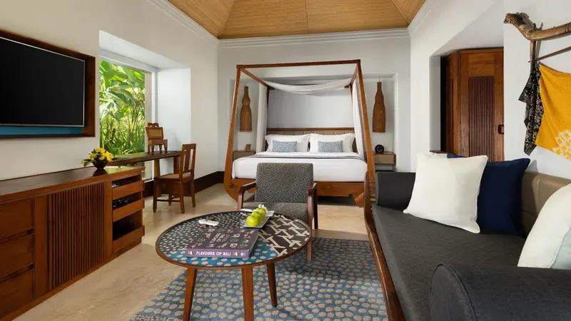 Une chambre lumineuse avec un grand lit à baldaquin et un coin salon.
