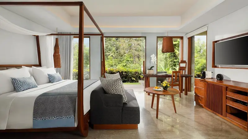 Une chambre lumineuse avec un grand lit à baldaquin donnant sur une végétation luxuriante.