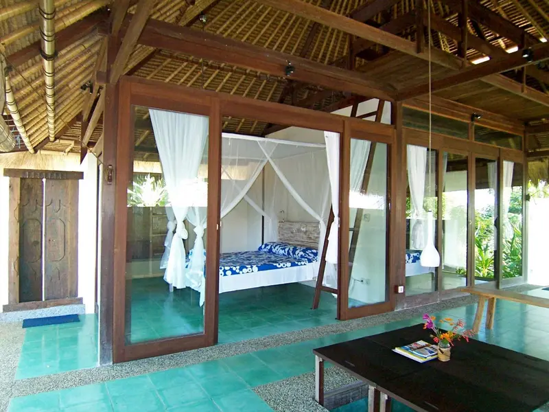 Une chambre lumineuse avec un lit à baldaquin et une décoration tropicale.