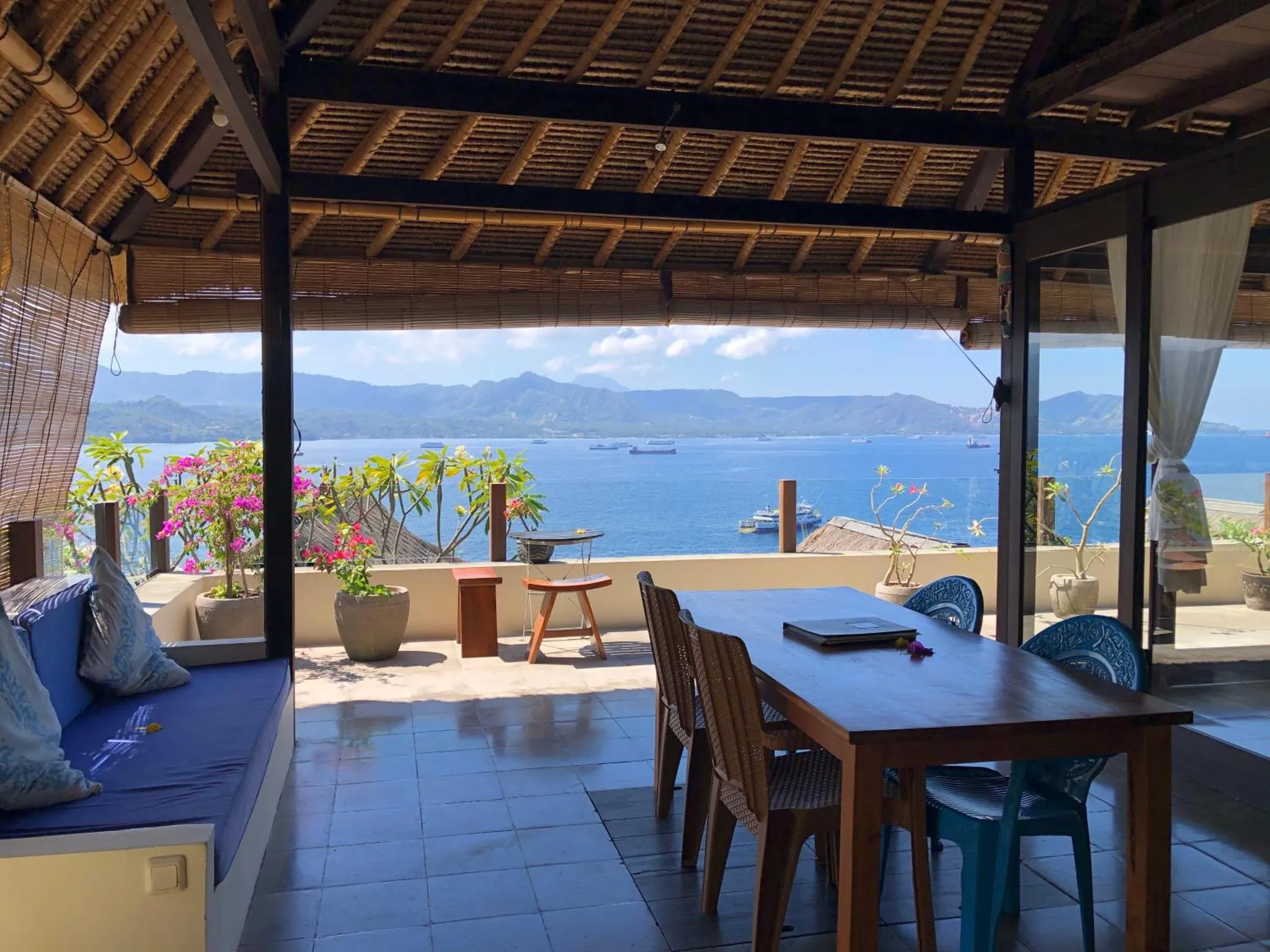 Terrasse ombragée avec coin repas et vue sur la mer.