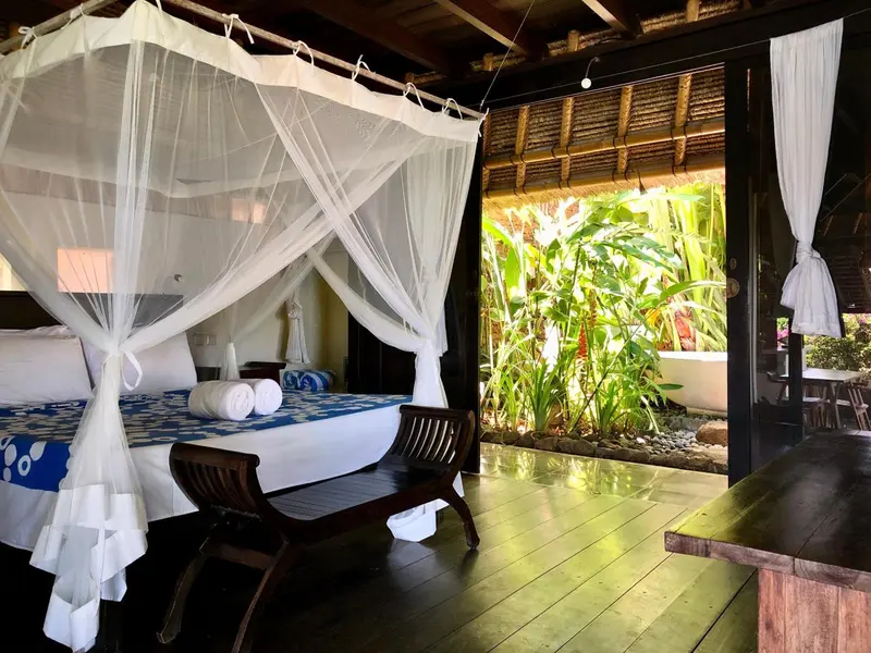 Une chambre avec un lit à baldaquin donnant sur une végétation luxuriante.
