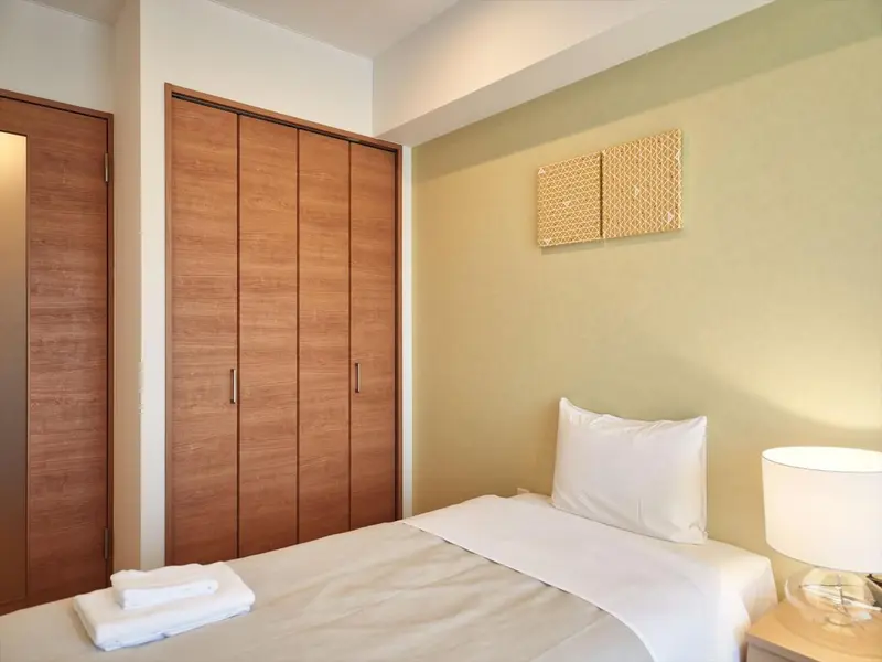 Une chambre lumineuse avec un lit simple et une armoire en bois.