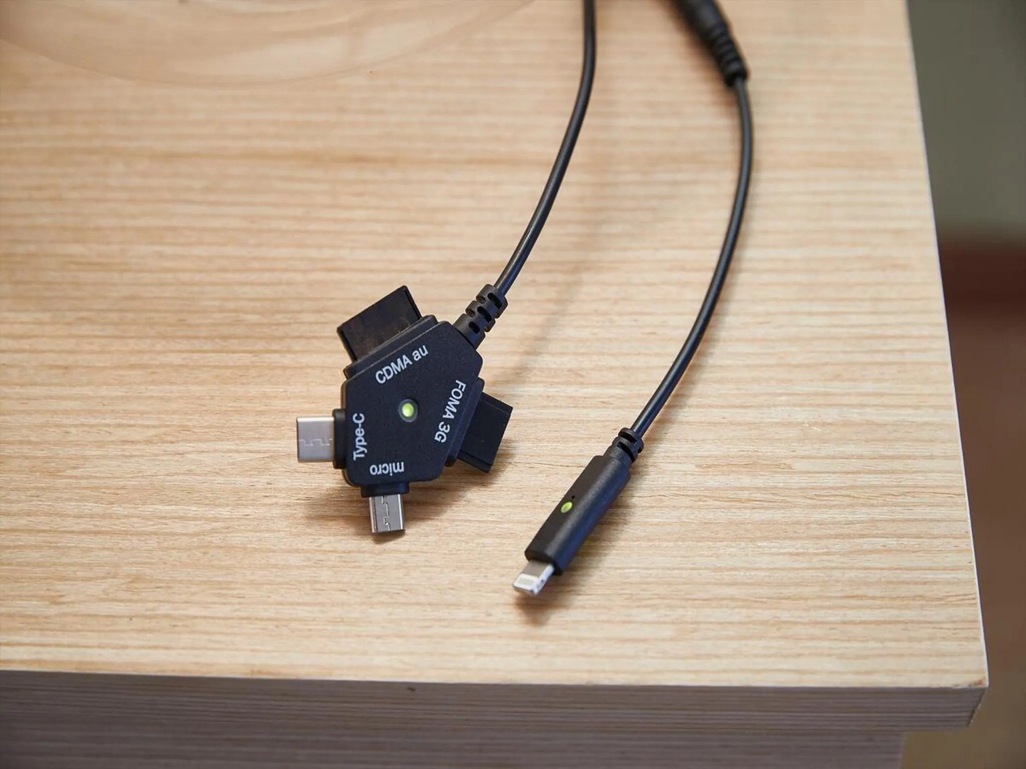 Adaptateur de connecteurs pour appareils mobiles sur une surface en bois clair.