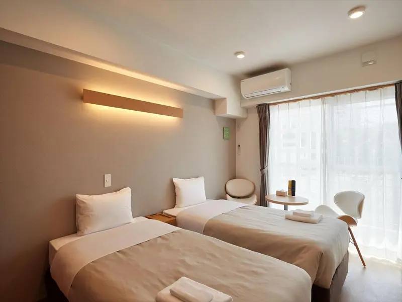 Une chambre lumineuse avec deux lits simples et une fenêtre.